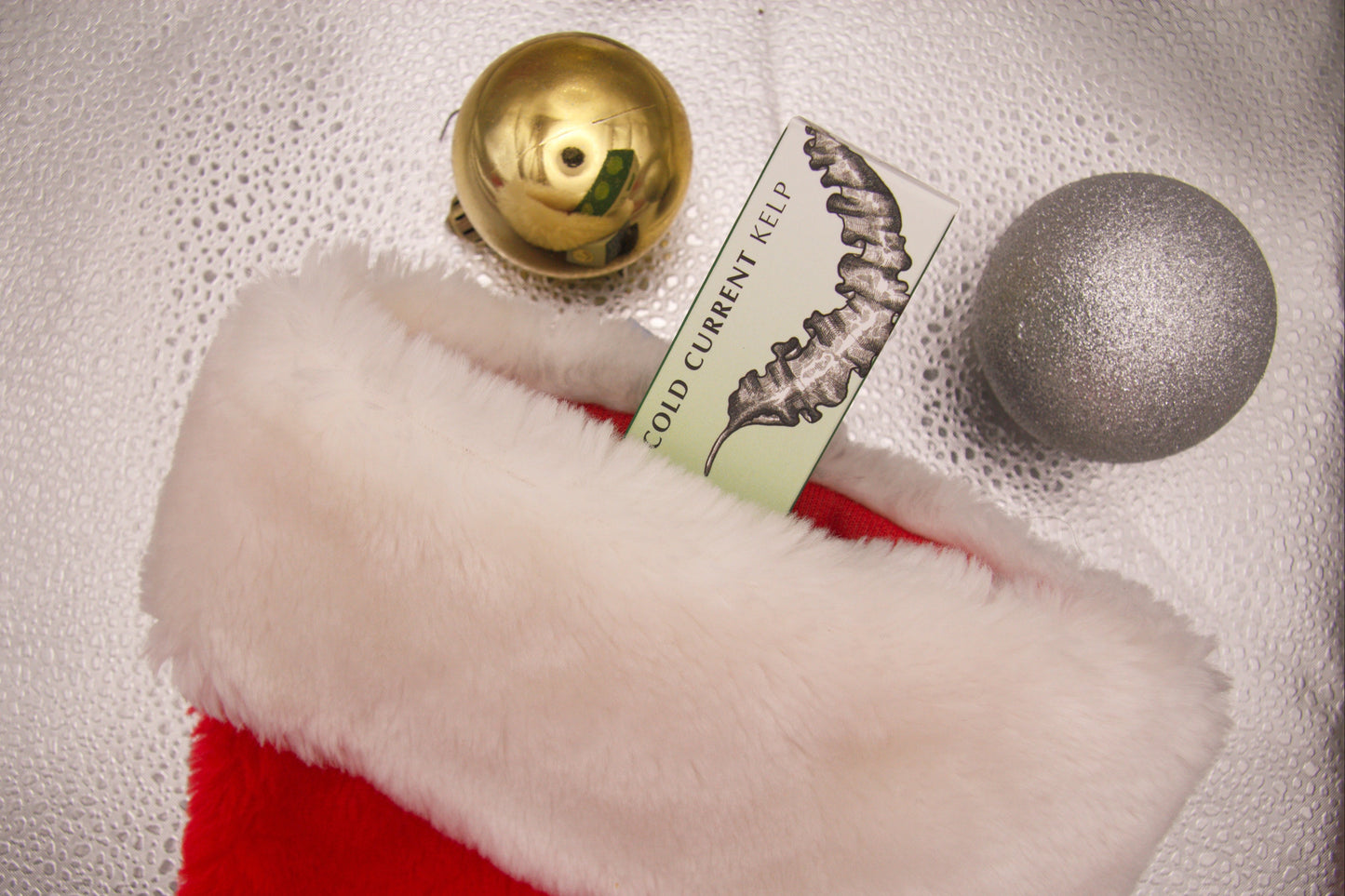 Red and white Christmas stocking with gold and silver ornaments on a textured surface